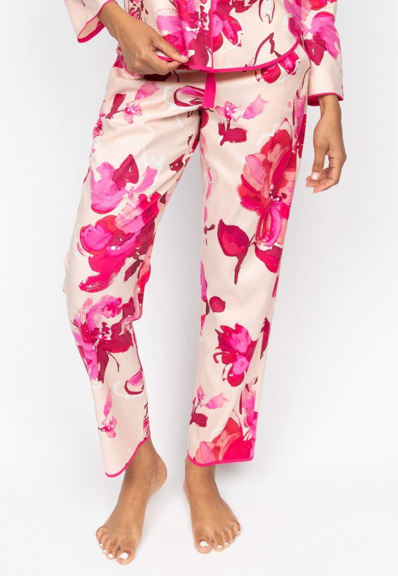 Floral pyjama set in roze en beige kleuren, met een losse top en bijpassende broek. De stof heeft een soepele textuur en contrasterende roze afwerking.
