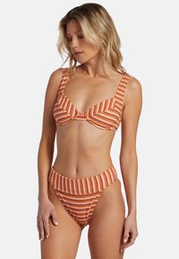 Ensemble de bikini rayé en orange et blanc, comprenant un haut avec armature et bande, ainsi qu'un bas taille haute à texture côtelée.