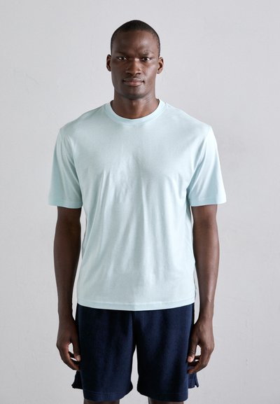 Tricou scurt, de culoare albastru deschis, dintr-un material moale, cu guler rotund. Asortat cu pantaloni scurți de culoare bleumarin închis, creând o ținută casual.