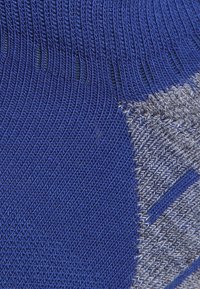 Calza blu in maglia caratterizzata da un motivo a coste, con una sezione grigia testurizzata a contrasto che evidenzia le righe diagonali.