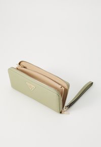 Portefeuille en cuir vert avec une finition texturée, ferrures dorées et une attache de poignet. Dispose d'une fermeture éclair et d'un intérieur beige avec des compartiments.