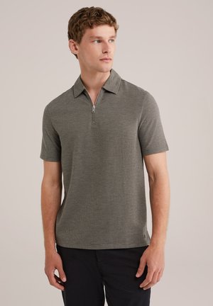 Polo de manga corta en gris oscuro, con un cuello con cremallera, tejido texturizado y un corte relajado. Complementado con unos pantalones cortos negros elegantes.
