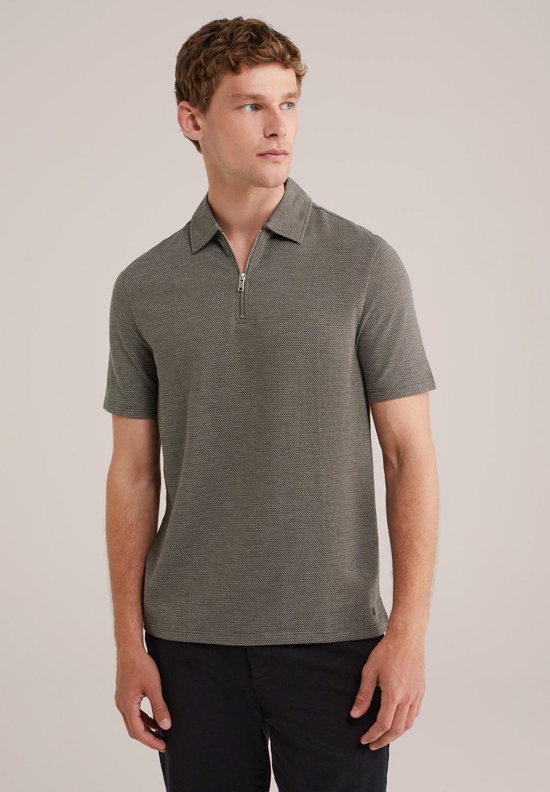 Polo de manga corta en gris oscuro, con un cuello con cremallera, tejido texturizado y un corte relajado. Complementado con unos pantalones cortos negros elegantes.