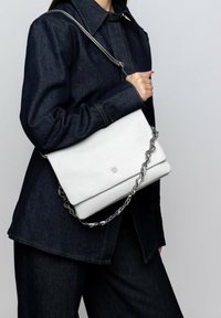 Borsa a tracolla bianca in pelle con una catena, design strutturato e superficie liscia. Presenta un logo goffrato discreto sul davanti.