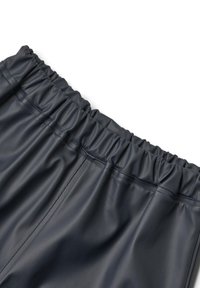 Close-up of black elastic waistband on smooth faux leather pants with visible stitching details on white background.