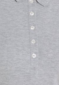 Szary polo z teksturowanym splotem, klasycznym kołnierzykiem i sześcioma białymi plastikowymi guzikami na przedniej listwie.