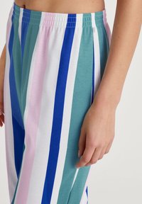 Gestreepte loungebroek met verticale patronen in teal, blauw, roze en wit. Gemaakt van zachte stof met een elastische tailleband.