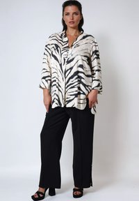 Zebra-print, lichtgewicht shirt met een kraag en driekwart mouwen, gecombineerd met zwarte, recht gesneden broeken en zwarte platformhakken.