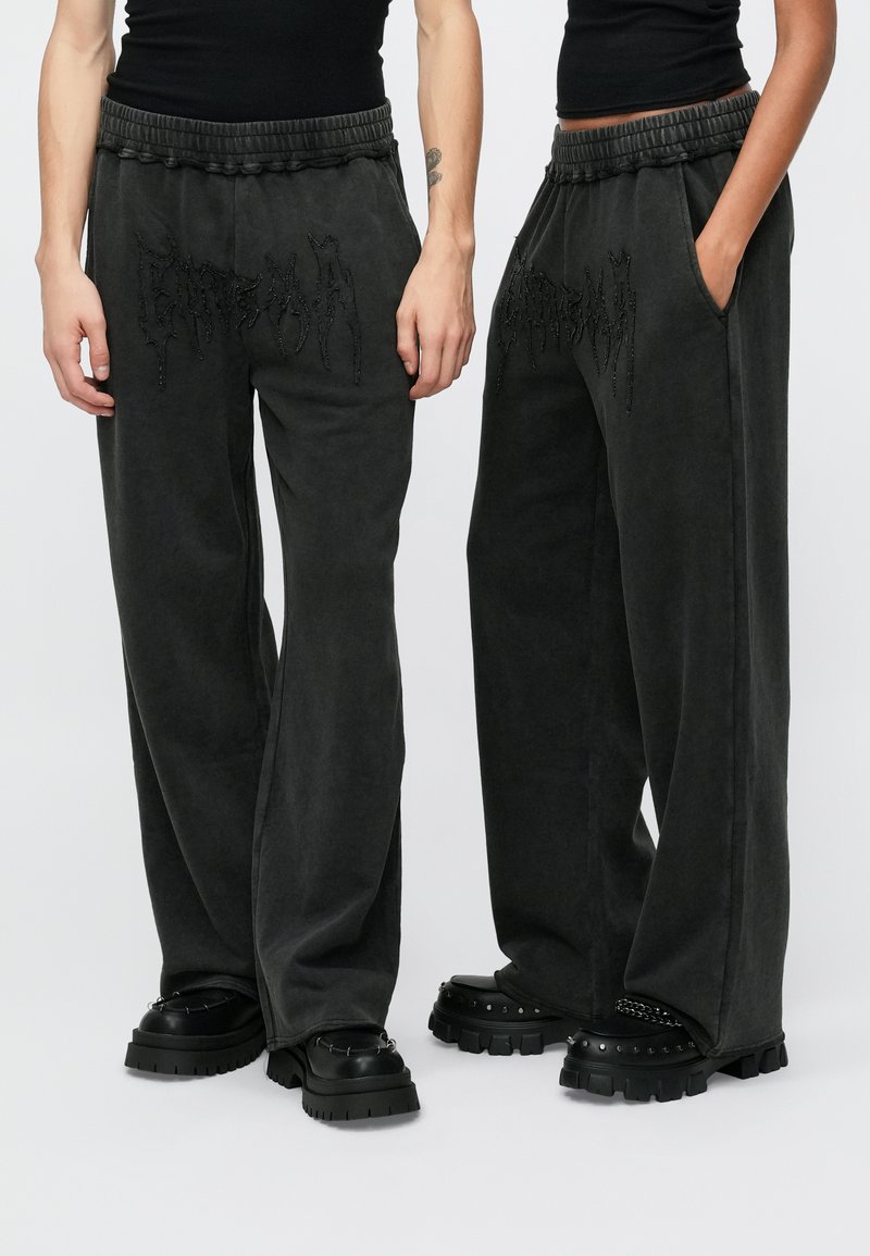 Tummanharmaat verkkarit rentolla istuvuudella, joustavalla vyötäröllä, sivutaskuilla ja etuosassa teksturoiduilla mustilla logodetaljeilla.