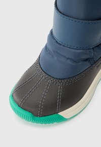 Schneestiefel mit einem unteren Teil aus schwarzem Leder, einem oberen Teil aus blauer Nylon und einer grünen Gummisohle. Merkmale sind ein gepolstertes Design mit sichtbaren Nähten.