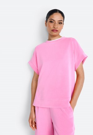 Roze top met korte mouwen, gemaakt van zachte stof, met een ronde hals en een ontspannen pasvorm, gecombineerd met bijpassende broek in dezelfde kleur.