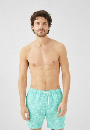 Shorts de bain turquoise avec des motifs géométriques blancs, dotés d'une taille élastique avec cordon de serrage et d'une coupe décontractée.