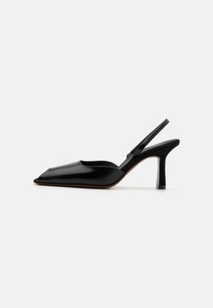 Czarne skórzane czółenka typu slingback z wąskim noskiem, minimalistyczny design, cienki pasek wokół kostki i elegancka szpilka. Gładka tekstura.