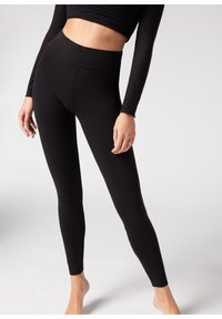 Leggings negros con cintura alta, hechos de material elástico; diseño ajustado y textura suave sin patrones o acentos visibles.
