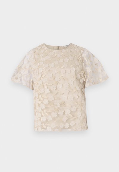 Beige blouse met bloem borduursels, doorschijnende pofmouwen, ronde halslijn en rits op de rug. Getextureerd bloemmotief op het voorpaneel.