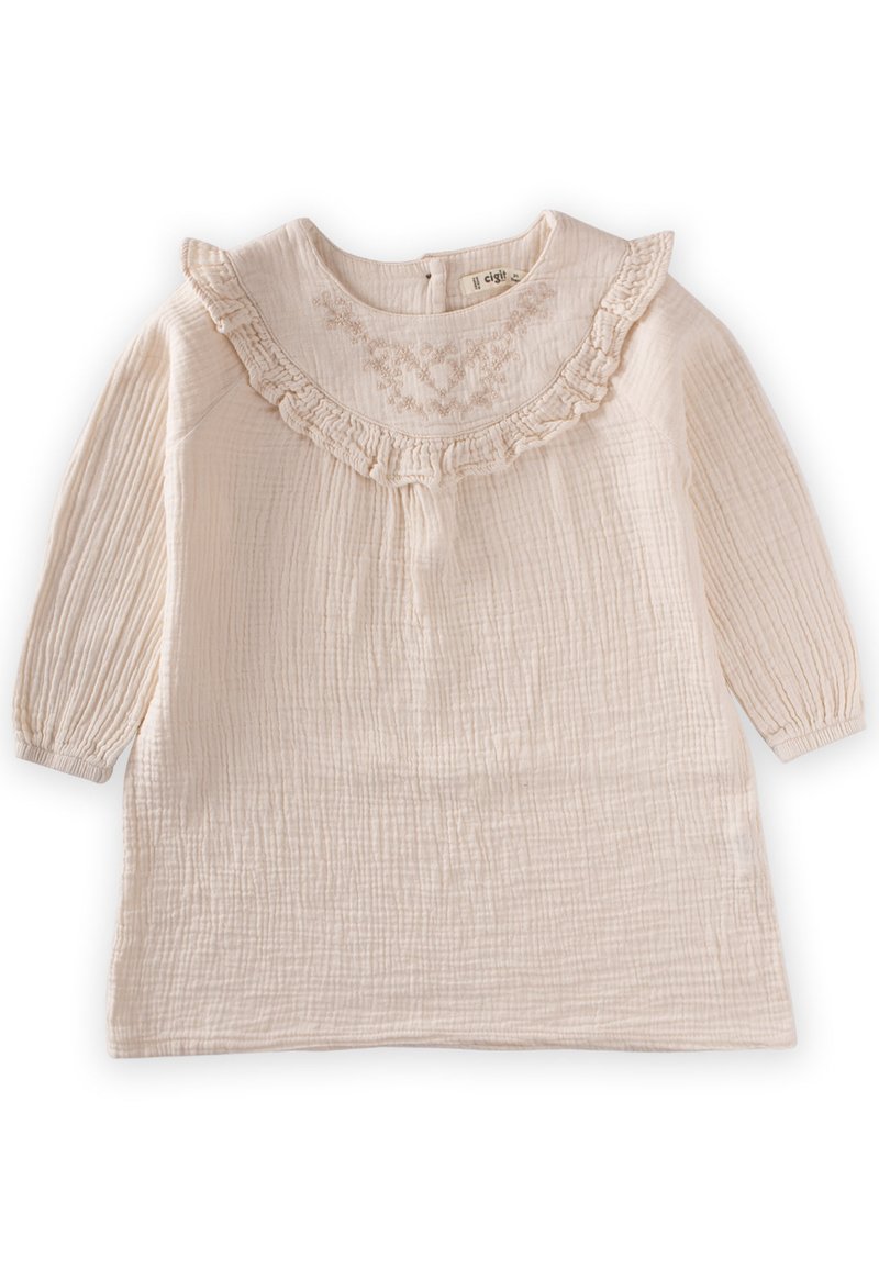 Helles beige Kleid mit langen Ärmeln, einem Rüschenausschnitt und strukturiertem Stoff, der zarte Stickereien auf der Vorderseite aufweist.