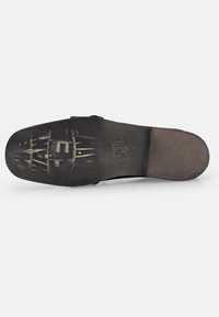 Black shoe sole with a smooth surface and textured pattern, including a logo imprint and stylized designs for traction.