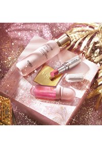 Serum Kiko Milano Hydra Pro Glow, różowa szminka, błyszczyk do ust oraz złote lusterko na błyszczącym różowo-złotym tle.