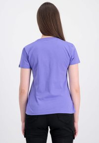 Lilla kortærmet t-shirt med rund halsudskæring og lige kant. Blødt stof med en glat tekstur, båret med sorte bukser.