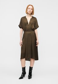 Φόρεμα μέσης μήκους σε ελιά πράσινο χρώμα με βαθύ V-λαιμόκοψη και κοντά, φαρδιά μανίκια. Κατασκευασμένο από λείο ύφασμα, διαθέτει στενή μέση και αέρινη φούστα.