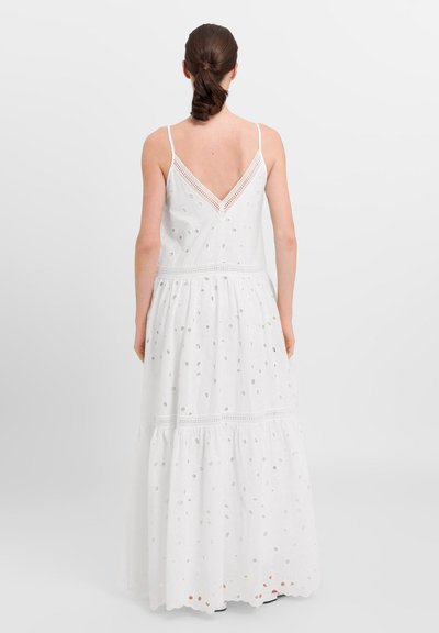 Rochie maxi albă cu spate în V, cu modele perforate, bretele reglabile subțiri și o fustă în straturi cu dantelă la talie.