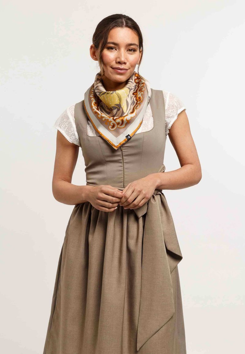Brown linen dress with a fitted bodice and loose skirt. A patterned silk scarf in shades of yellow and cream with orange detailing is worn around the neck.
