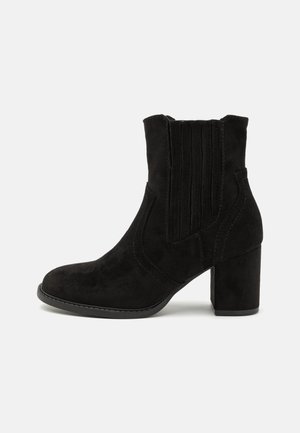 Black suede ankle boot with a block heel, textured side panels, and elastic gore for easy on/off. Smooth sole and reinforced stitching details.