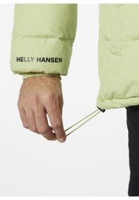 Světle zelená péřová bunda s elastickými manžetami a stahovací šňůrkou. Na rukávu je černě vytištěné logo "Helly Hansen". Strukturovaná tkanina.