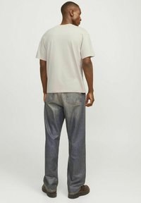 Lys grå bomulds t-shirt med en afslappet pasform, korte ærmer og rund halsudskæring, parret med løse blå jeans og brune sko.