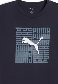 Tamsiai mėlynas medvilnės marškinėliai su grafiniu dizainu, kuriame žodis "PUMA" šviesiai mėlyna spalva ir baltas šuoliuojančio puma logotipas centre.