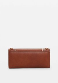Brown leather cylindrical pouch with visible stitching details and decorative white accents, featuring a smooth texture and minimalist design.