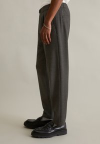 Gray tailored trousers made of textured fabric, featuring a straight-leg design, side pockets, and a subtle, clean finish. Paired with black loafers.