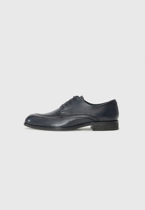 Navy leather dress shoe with a rounded toe, low heel, five eyelets, and subtle stitching details along the sides. Smooth texture.