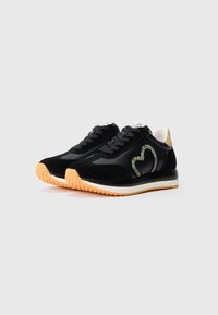 Sorte sneakers med overdel i semsket skinn og lær, med et hjerteformet rhinstein-design, en beige hæl og en teksturert oransje gummisåle.