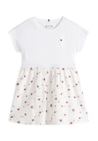 Λευκή βαμβακερή μπλούζα με κοντά μανίκια, συνοδευόμενη από φούστα σε κρεμ χρώμα με μικρά κόκκινα λουλούδια και μπλε λεπτομέρειες. Διαθέτει κεντημένη ετικέτα με λογότυπο στο στήθος.