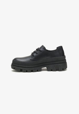 Zapatos de cuero negro con puntera redondeada, cierre con cordones y una suela de goma gruesa y texturizada con un patrón de dibujo.