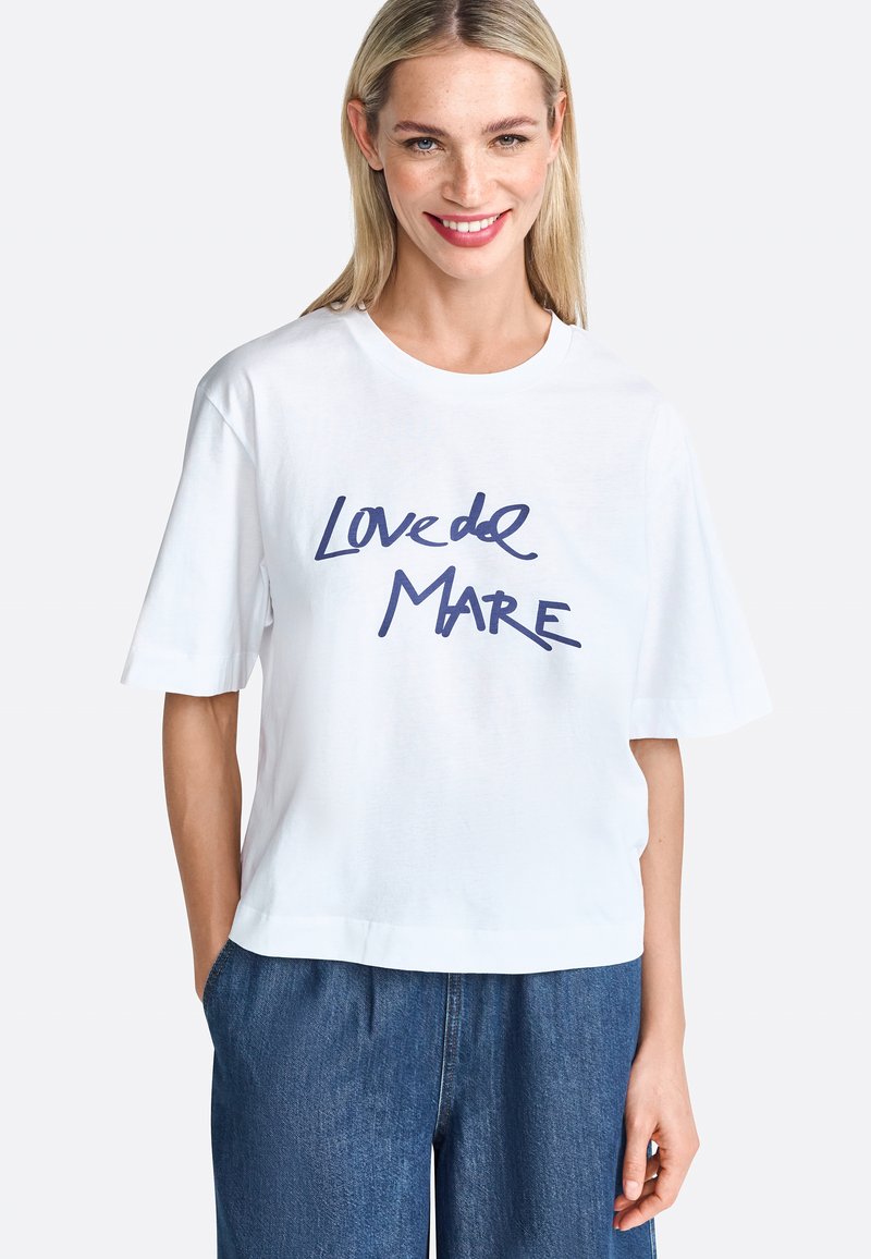 Weißes Baumwoll-T-Shirt mit kurzen Ärmeln, mit blauer handgeschriebener Aufschrift "Loved de Mare" auf der Vorderseite. Entspanntes Design.