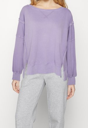 Paarse oversized sweatshirt met lange mouwen, verlaagde schouders, geribde manchetten en zijsplitten. Glad textuur en casual pasvorm.