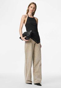 Melna haltera topiņš ar mežģīņu apdari, kopā ar gaiši bēšām plašām džinsa biksēm un melniem augstpapēžu apaviem ar smailām purngalām, papildināts ar melnu rokassomiņu.