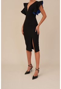 Robe noire ajustée avec un décolleté en V profond, des manches volantes avec des accents bleus, et une fente à l'avant. Assortie avec des escarpins noirs vernis.