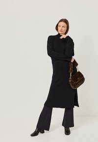 Rochie neagră tricotată cu guler înalt și manșete cu striații, asortată cu pantaloni întunecați largi și o geantă din blană sintetică cu imprimeu de leopard maro.