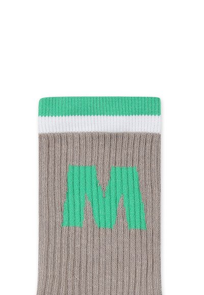 Calza grigia a costine con una lettera "M" verde, caratterizzata da una parte superiore a righe verdi e bianche. Texture morbida in maglia.