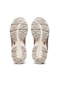 Idrottsskor med en texturerad grå ovandel, vita gummisulor med ett triangulärt mönster och integrerad dämpning.