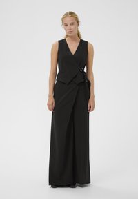 Čierny dámsky overal bez rukávov s zavinovacím dizajnom, detailom na boku s prackou, hladkou textúrou a strihom s širokými nohavicami.