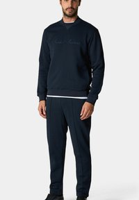 Granatowy sweter z ribbowanymi mankietami i dekoltem, z haftowanym logo "Brooks Brothers". W zestawie z dopasowanymi spodniami w tapered.