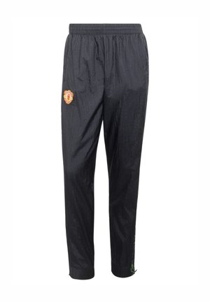 Mustat urheiluhousut joustavalla vyötäröllä, Manchester Unitedin logo vasemmassa reidessä ja vihreä nyöritys oikean nilkan kohdalla.