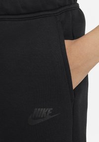 Svarta Nike joggerbyxor har en mjuk textur, sidoficka och en subtil svart logotyp på underbenet för varumärkeskännedom.