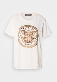 Camiseta blanca de manga corta con un diseño central de mariposa con acentos dorados y rosas, rodeado por un patrón decorativo circular.
