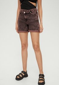 Denimowe szorty w wyblakłym czerwono-czarnym kolorze, z wysokim stanem i zrolowanym wykończeniem. Połączone z czarnymi, masywnymi sandałami z wieloma paskami i klamrą.