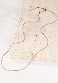 Collar de oro rosa con una cadena suave y flexible, que presenta un ligero brillo. Cuenta con un cierre simple y un diseño elegante.